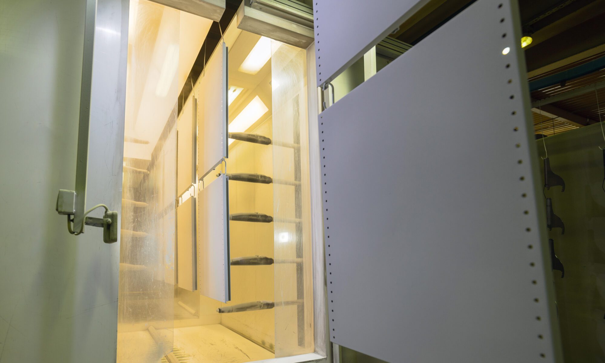 A number of powder-coated metal panels enter a post-dip curing chamber