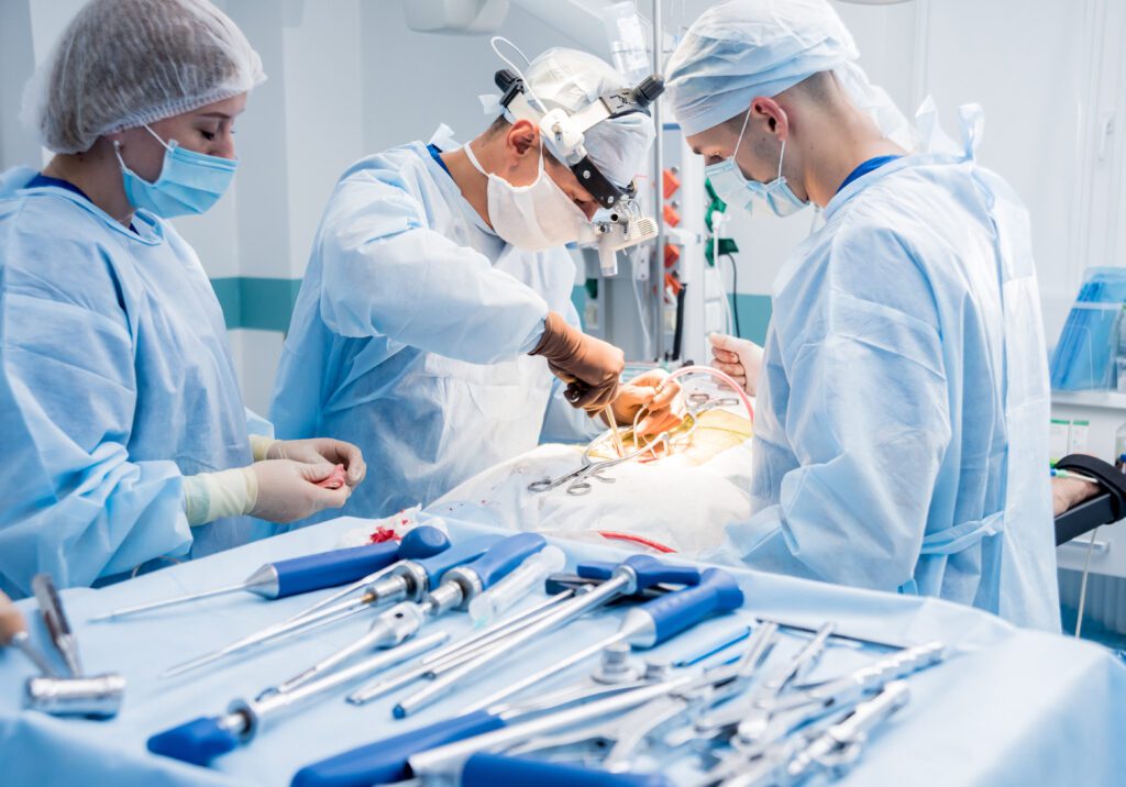 Surgical tools sit on a table next to a doctor performing surgery.