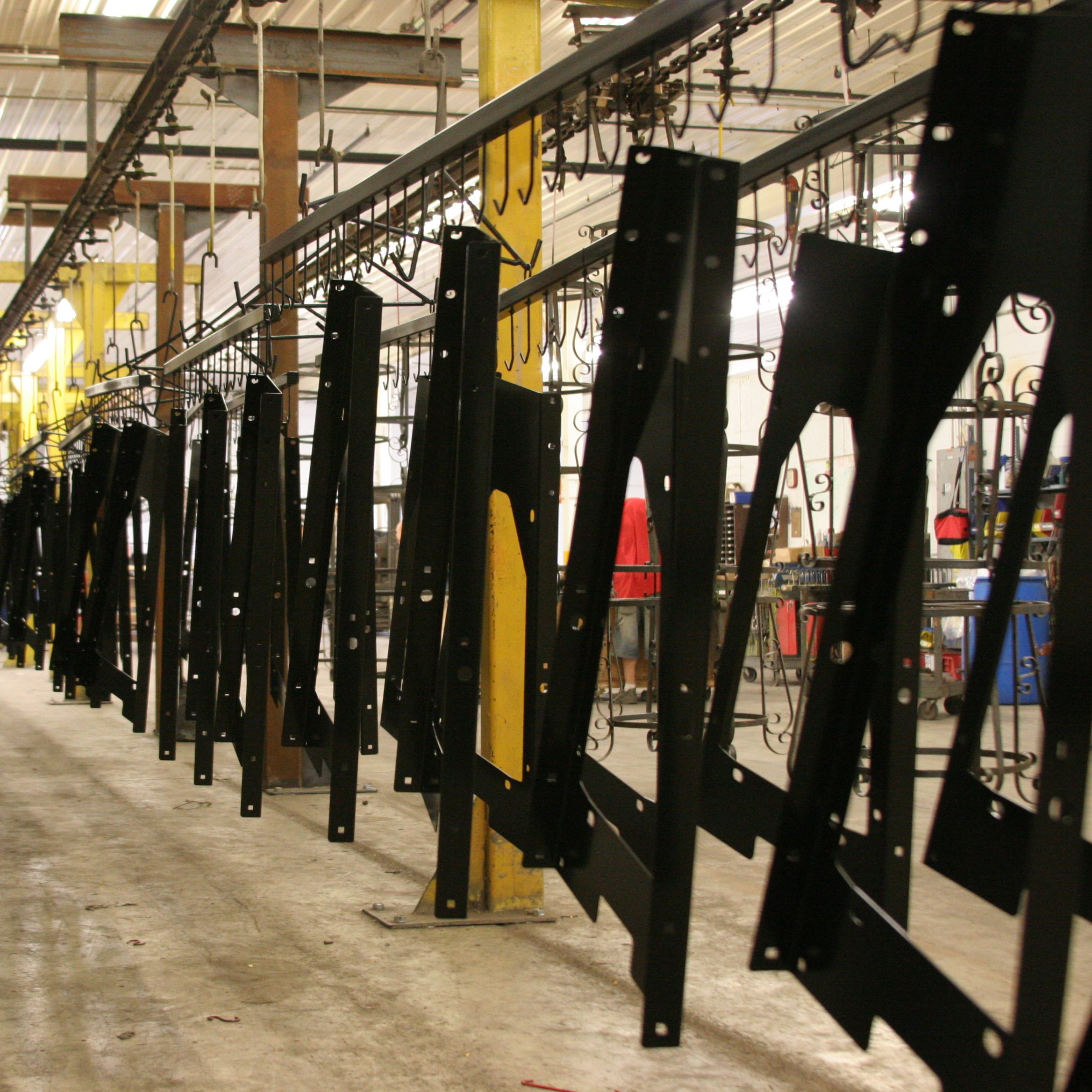 Metal parts hang on a powder coating conveyor line.