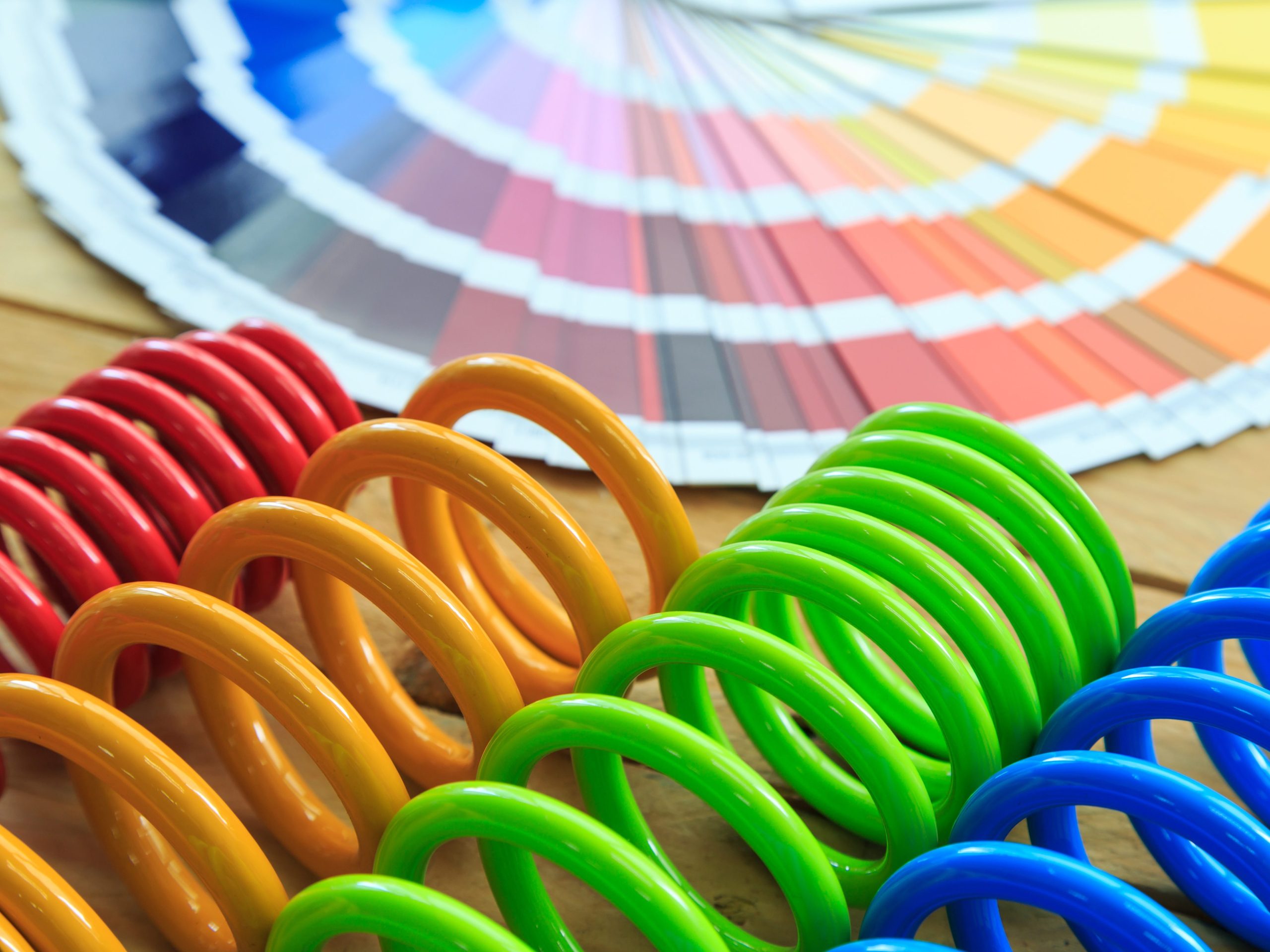 Red, orange, green, and blue PVC-coated springs in front of a spread-out set of color swatches.