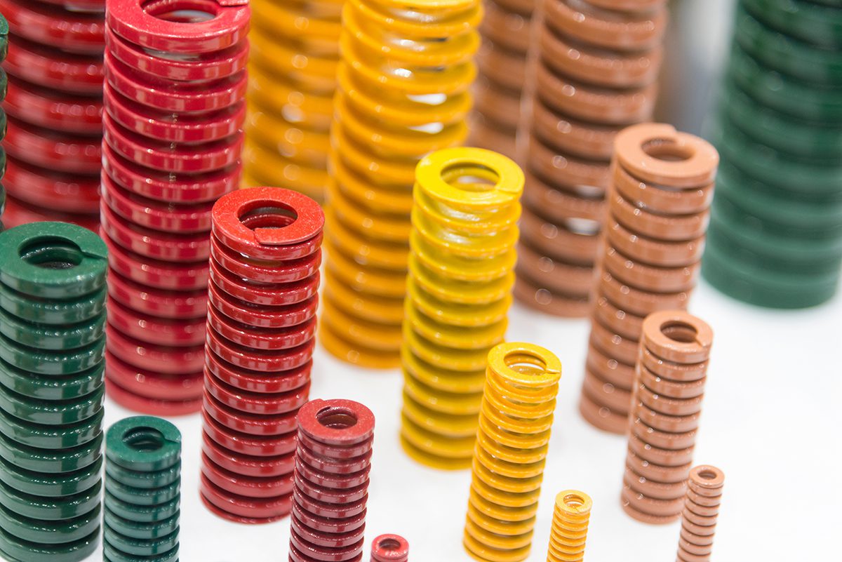 A display of industrial springs that have been coated with green, red, yellow, and brown powder coats