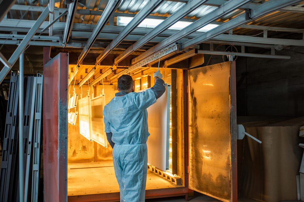 Man putting metal products in a powder coating oven.
